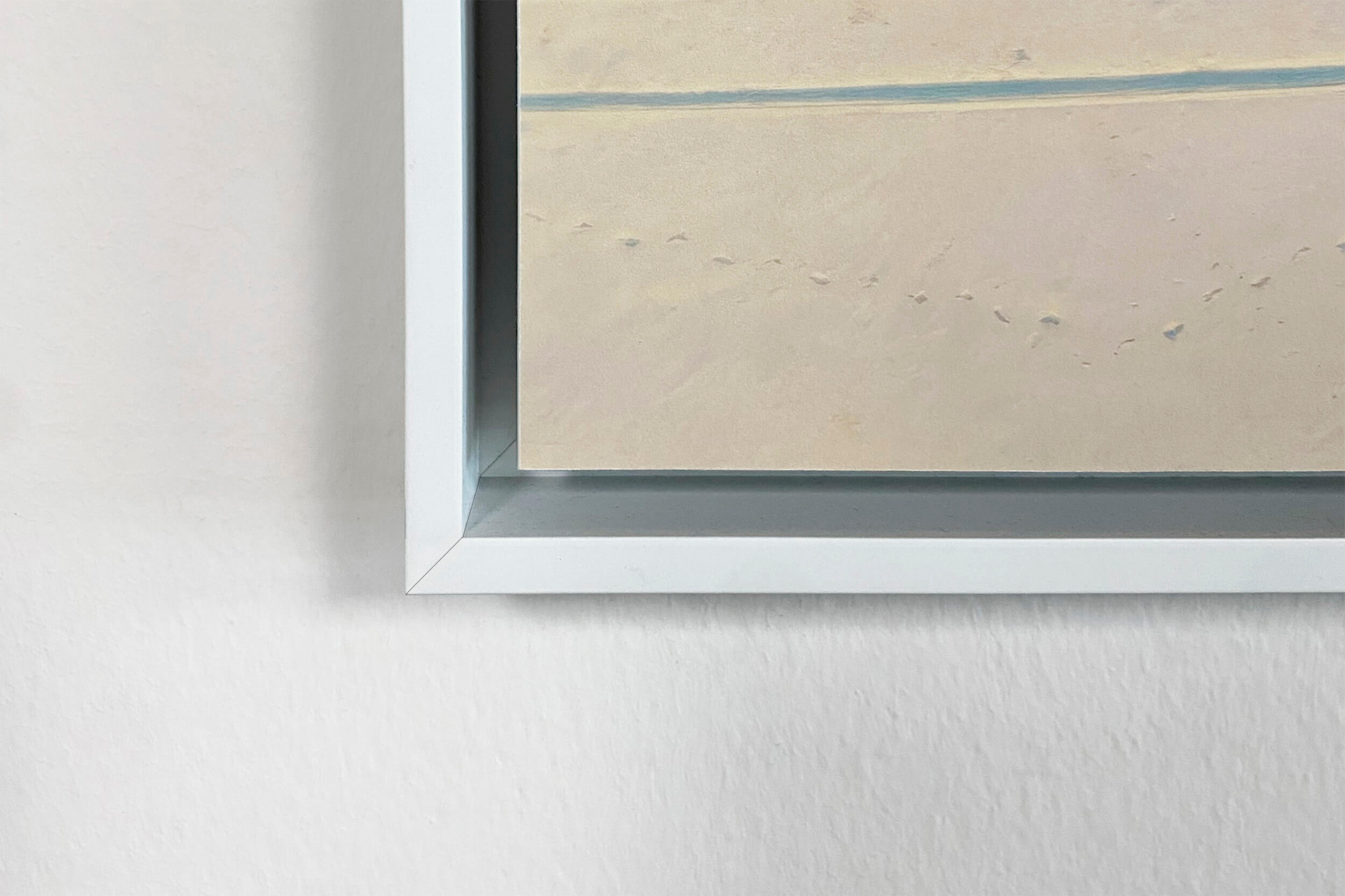 Corner detail of a white float frame on an acrylic print, showing the gap between the frame and the edge of the art